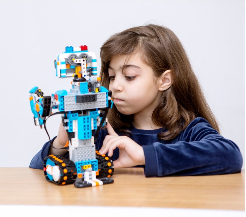 Flicka vid bord med lego-robot