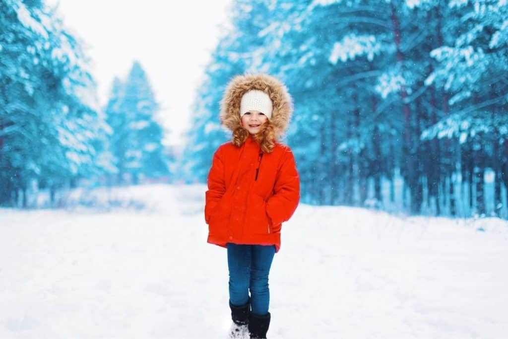 Barn med vinterjacka och pälshuva ute på vintern