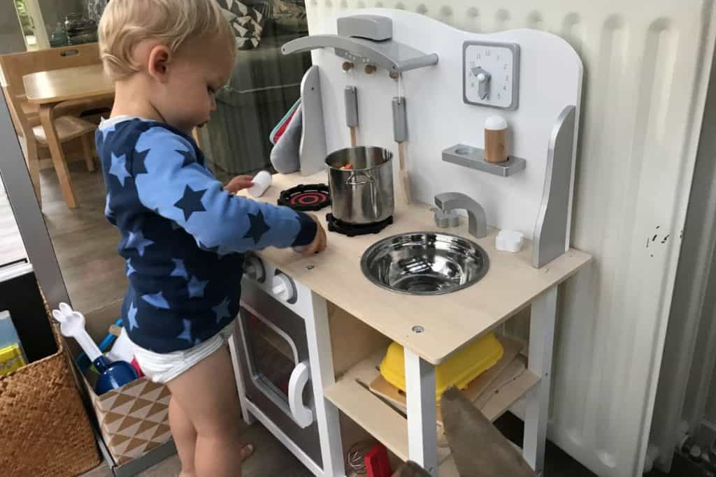 Litet barn står och leker med leksakskök