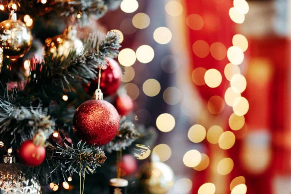 Julgran med pynt, suddigt ljus i bakgrunden