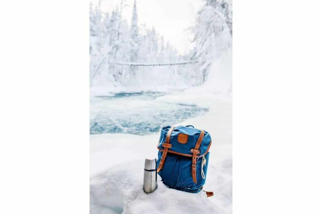 Ryggsäck och termos i snön på vinter