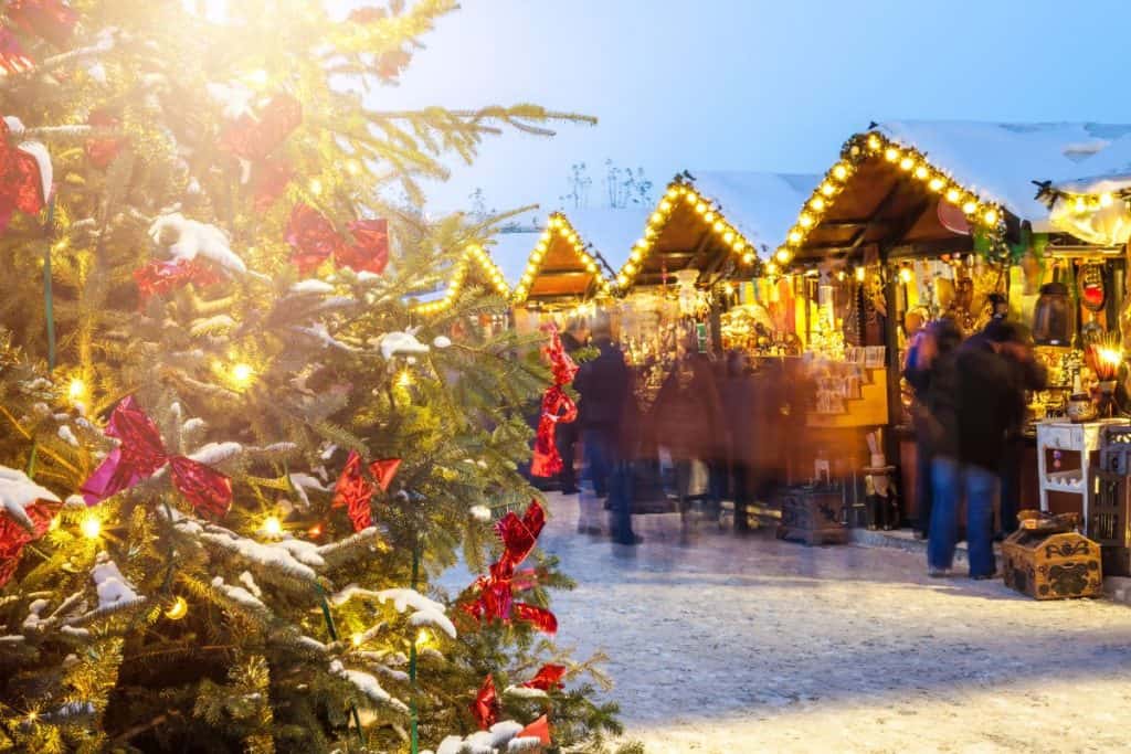 Julmarknad med gran, ljus och små stugor