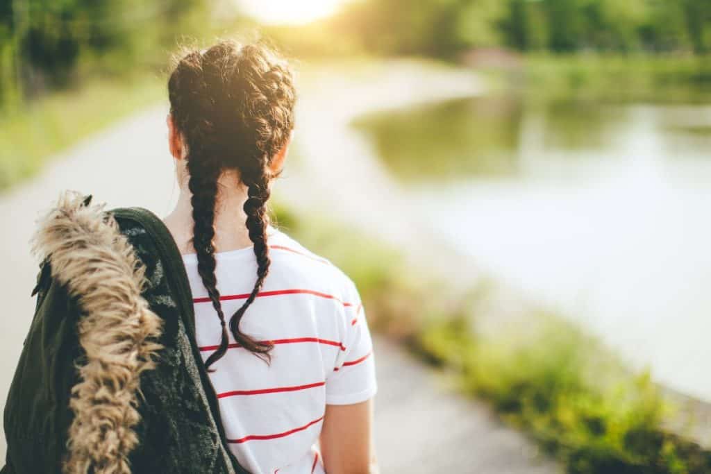 Flicka med jackan över axeln ute på promenad