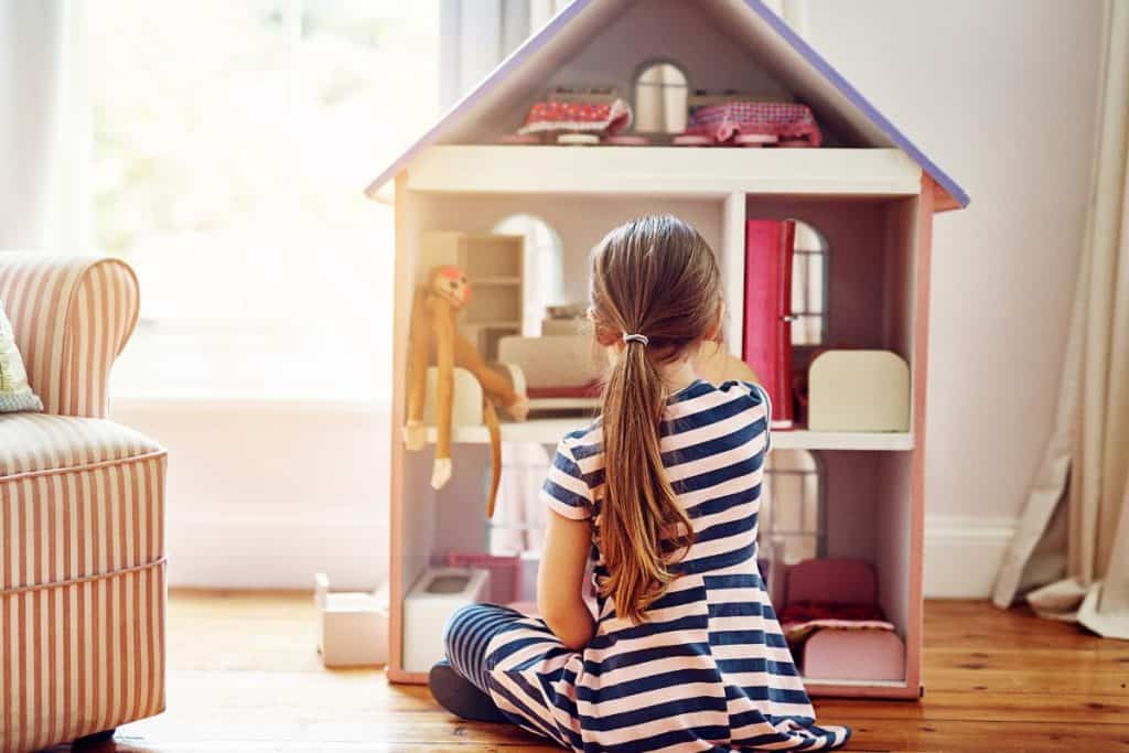 Flicka leker med stort dockhus