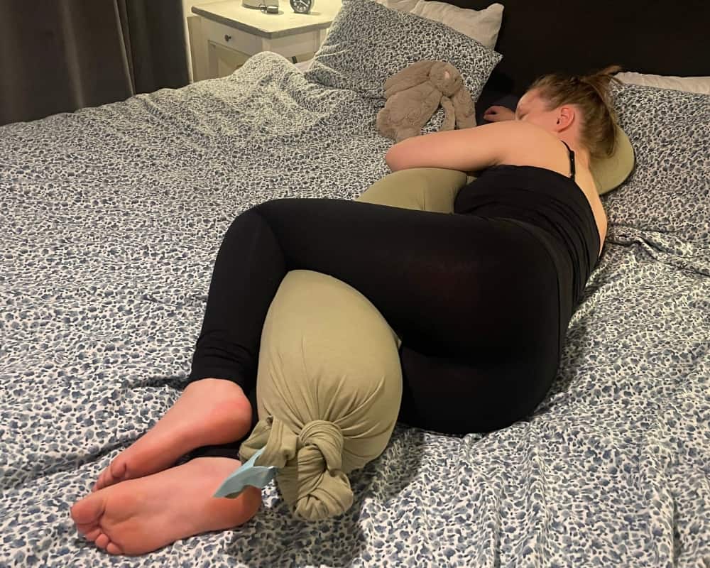 Kvinna ligger i säng med en kudde från Najell