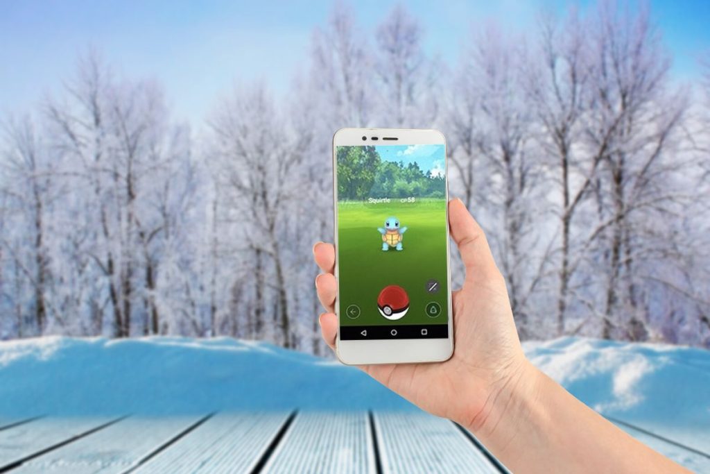 Pokemon GO på telefon i hande, vinterbakgrund